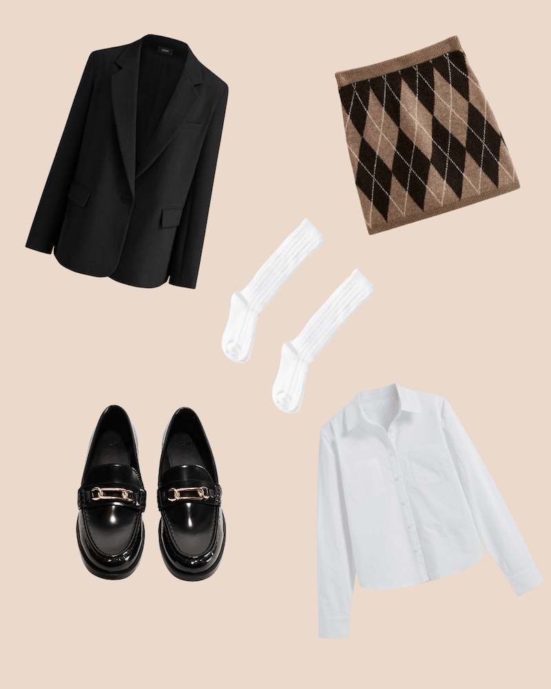 A flat lay of a black blazer, brown argyle mini skirt, white crew socks, black loafers with gold buckles, and a white button-up shirt arranged on a beige background channels fall fashion with classic looks fit for rom-com characters.